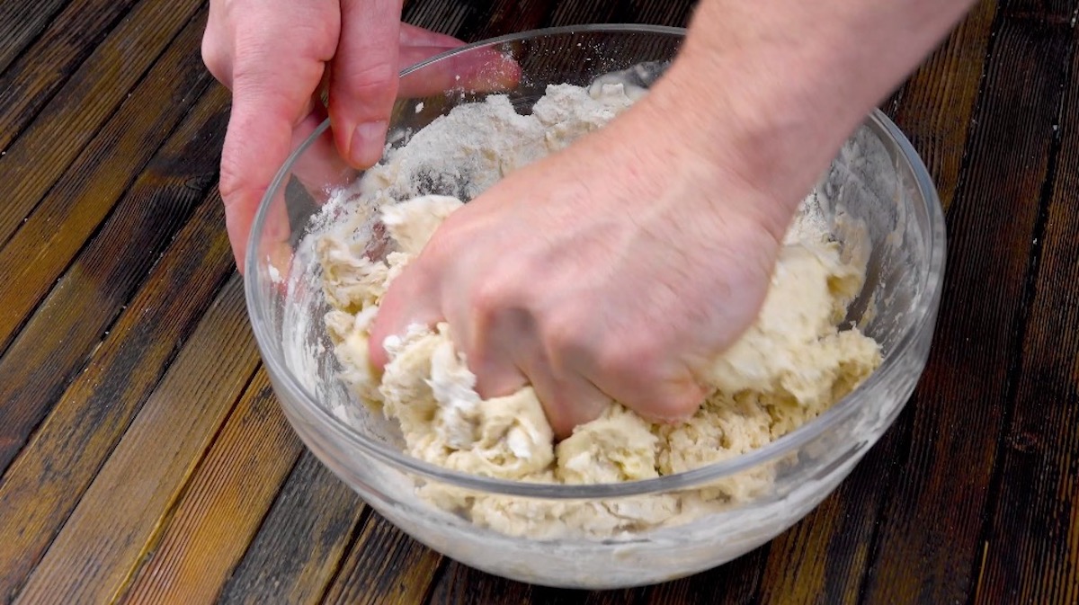 Brotteig wird in Schüssel mit Händen verknetet