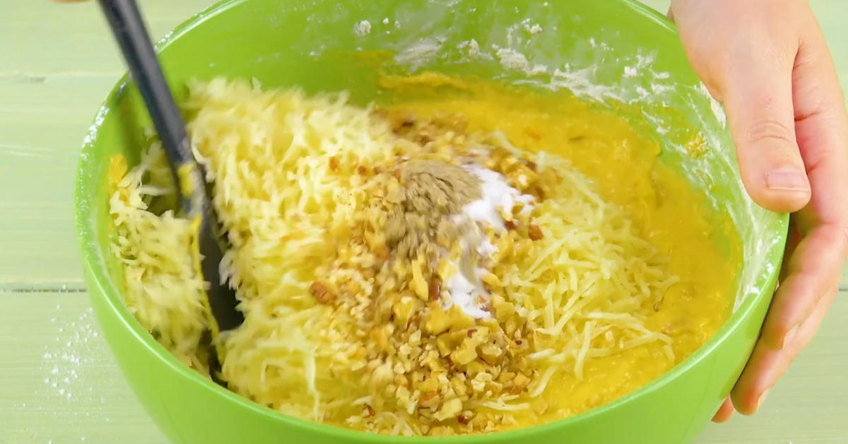 Kuchenteig wird mit Käse und klein gehackten Nüssen verfeinert