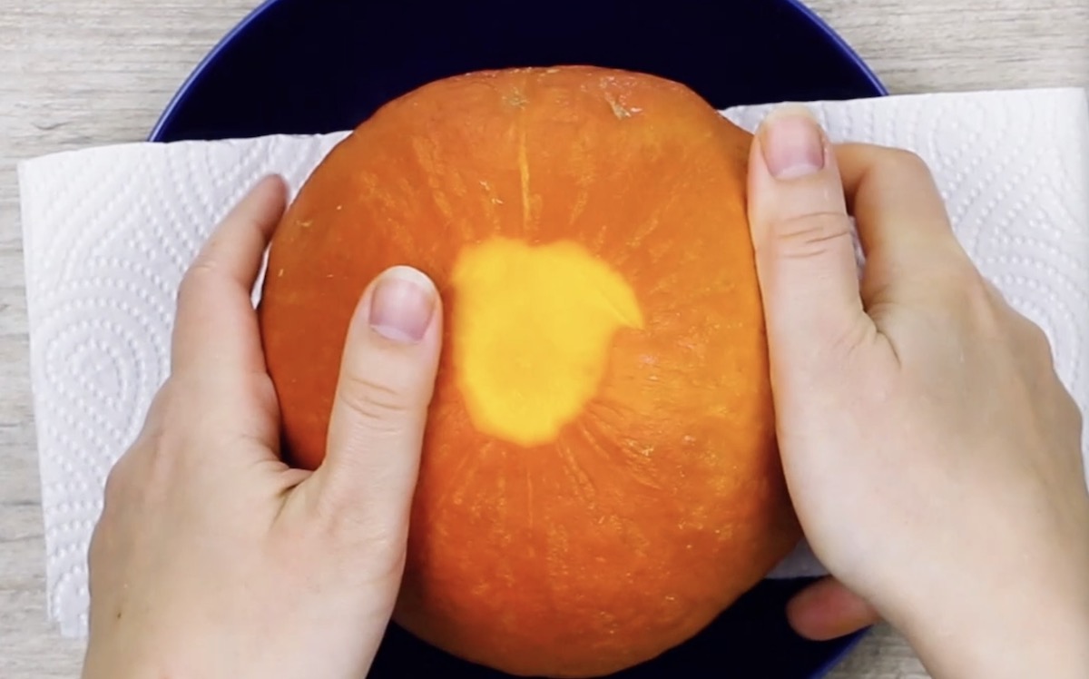 Ausgehöhlter Kürbis wird mit Öffnung nach unten auf Küchentuch gestellt