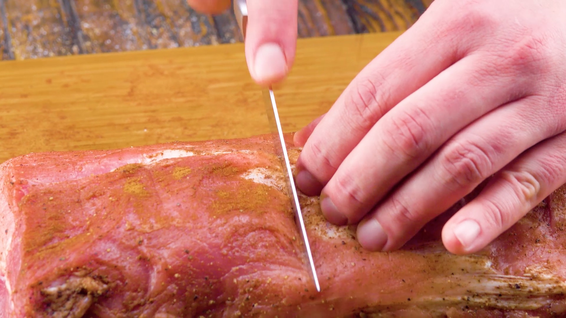 Schweinerücken wird mit einem Messer eingeschnitten.