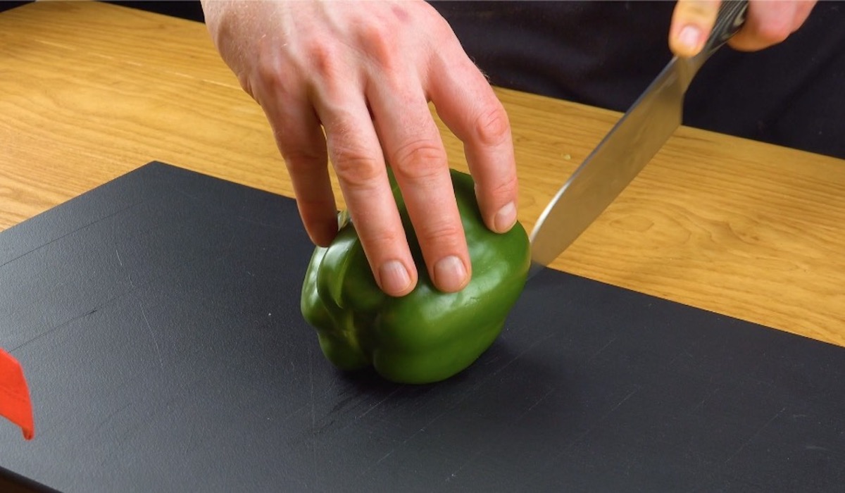 Grüne Paprika wird mit Messer halbiert