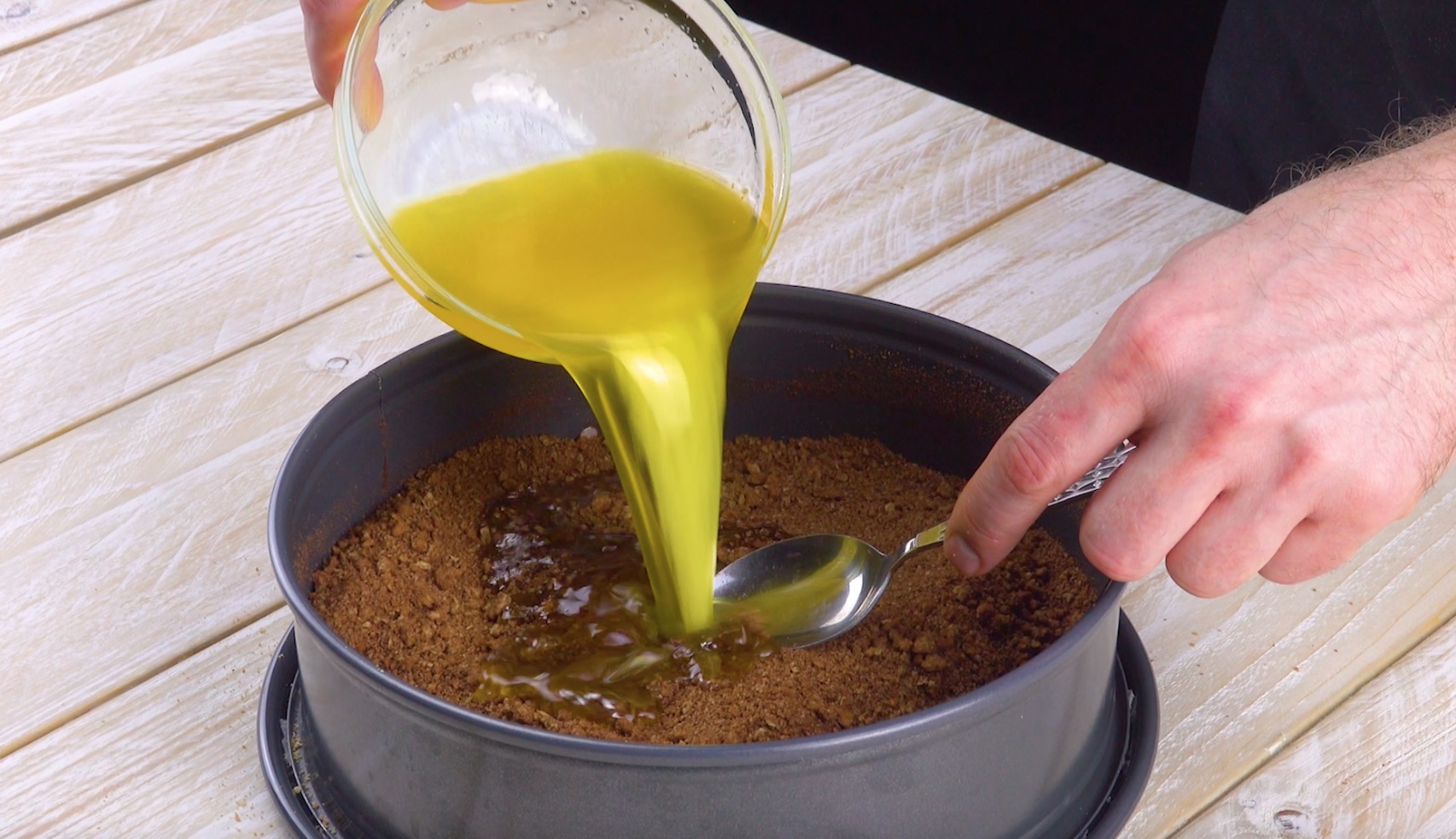 Flüssige Butter wird über Keksboden in Kuchenform gegossen