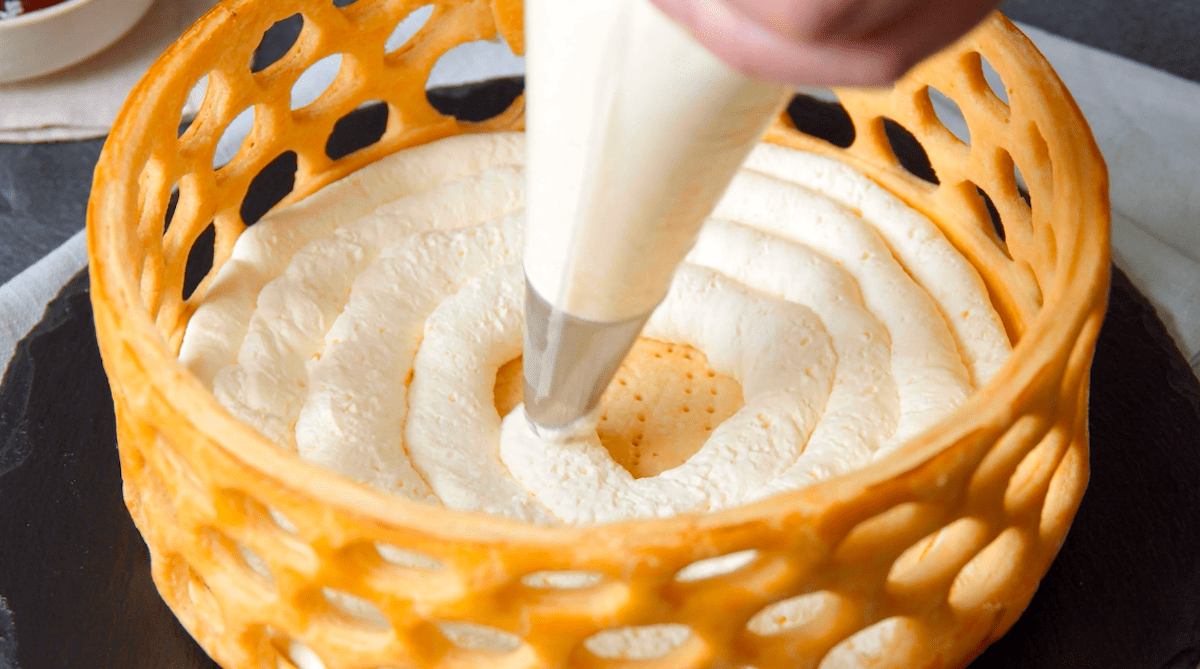 Frischkäsecreme wird in einen essbaren Teigkorb gespritzt