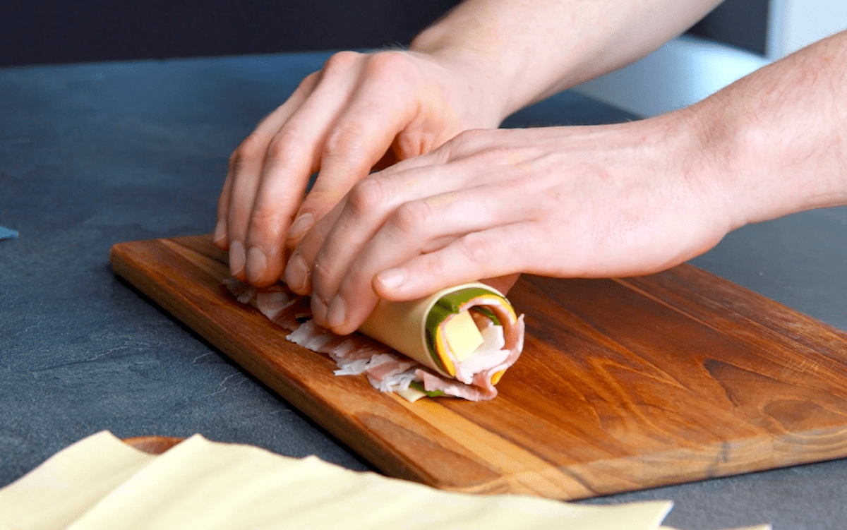 Eine Bacon-Käse-Rolle wird zusammengerollt