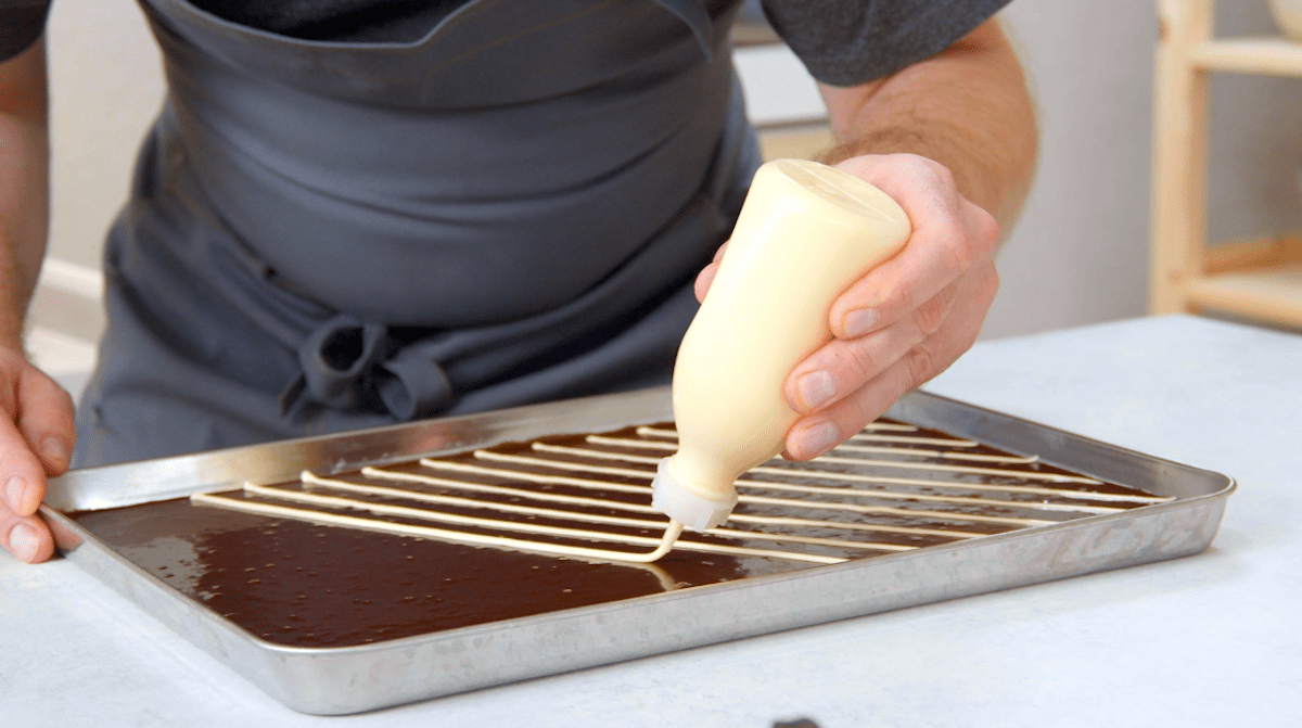 Puddincreme wird rautenförmig auf Schokoteig gegeben