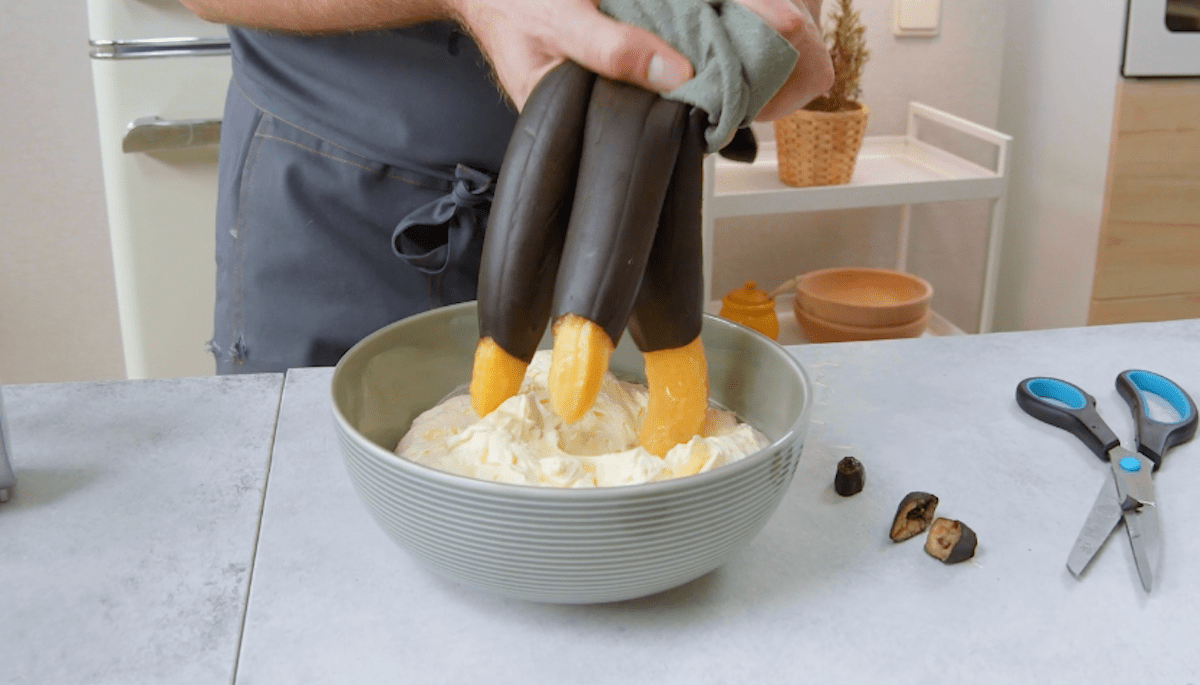 Gebackene Bananen werden über eine schüssel ausgedrückt