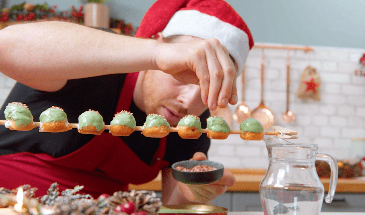 Windbeutel werden mit Kuvertüre und Zuckerstreusel verziert