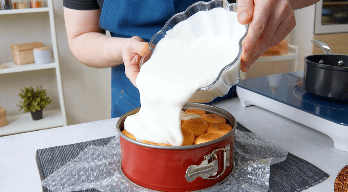 Frischkäsecreme wird über Windbeutel gegossen