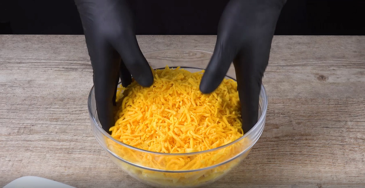 Pommes werden mit geriebenem Käse in Schüssel vermischt