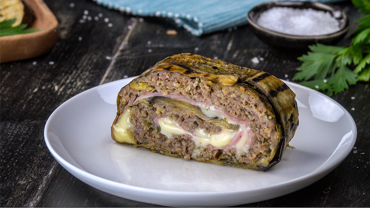 Ein Stück Auberginenrolle mit Hackfleisch und Käse auf Teller