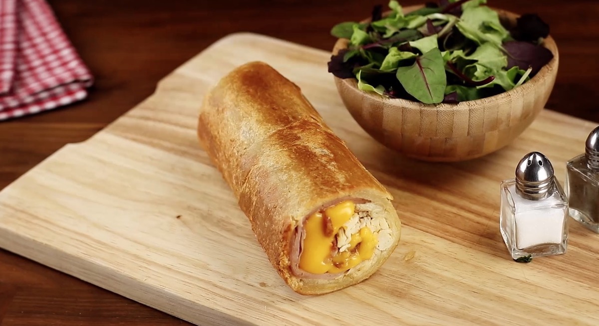 Eine Club-Sandwich-Rolle neben einer Schüssel Salat