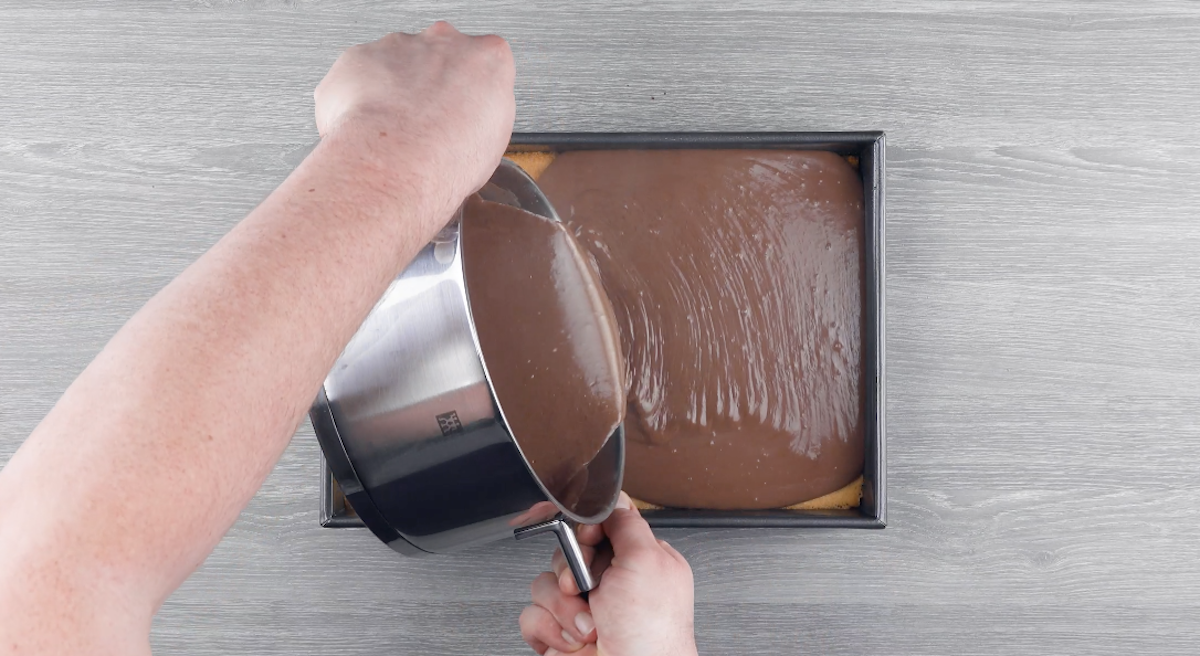Flüssiger Schokopudding wird auf Teig in Backform gegossen
