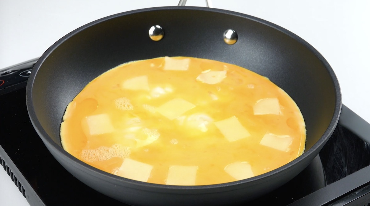 Omelett mit Käsestücken in Pfanne