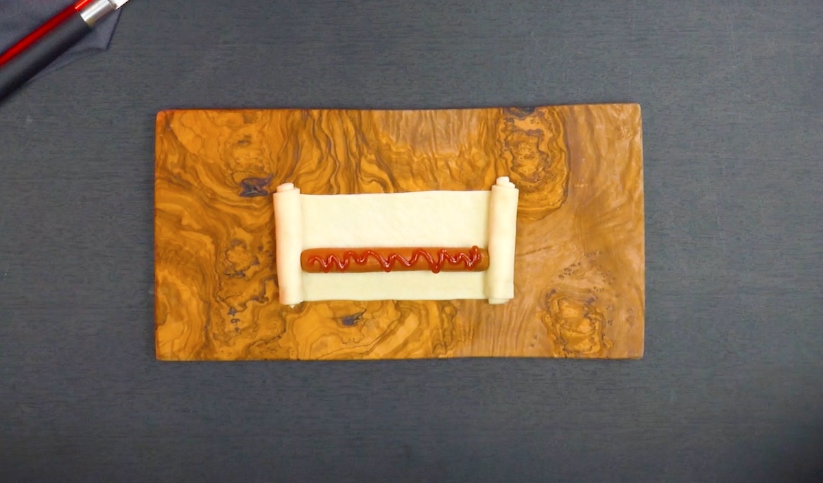 Würstchen auf Teig wird eingerollt