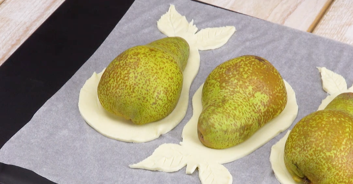 Halbierte Birnen werden auf ausgeschnittenen Blätterteig auf Backblech gelegt