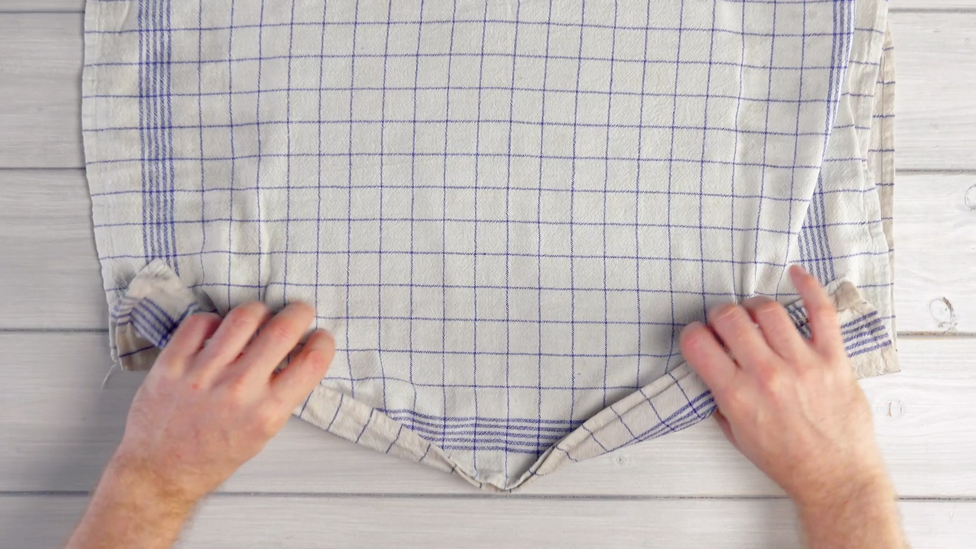 Ein feuchtes Geschirrtuch wir in beide Hände genommen