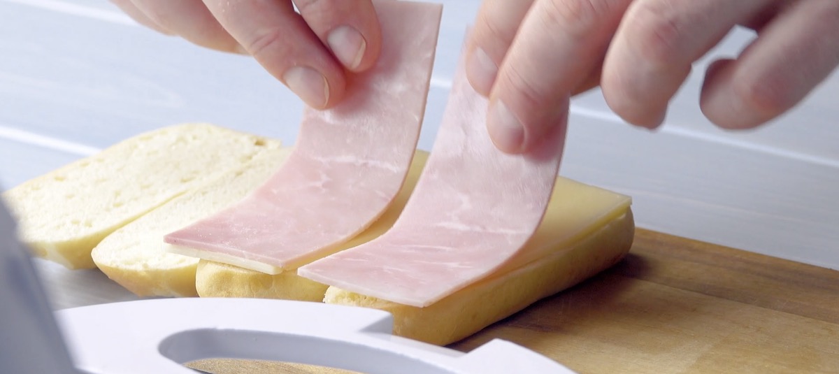 Milchbrötchenhälften werden mit Schinken und Käse belegt.