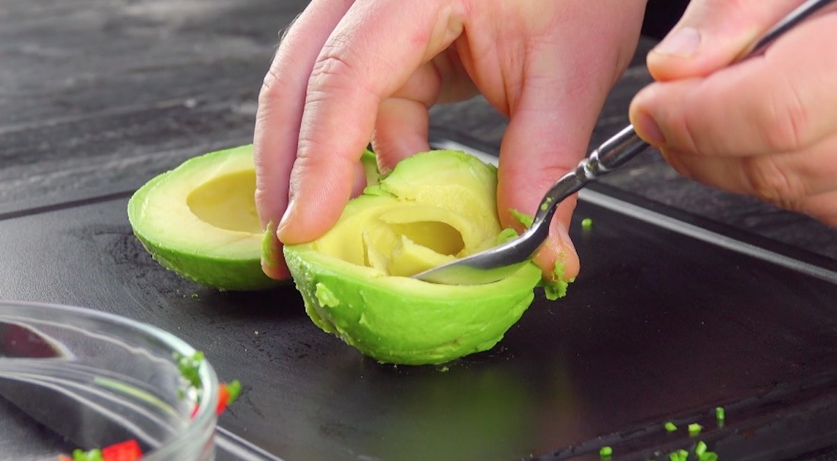 Avocadohälften werden mit Löffel ausgehöhlt