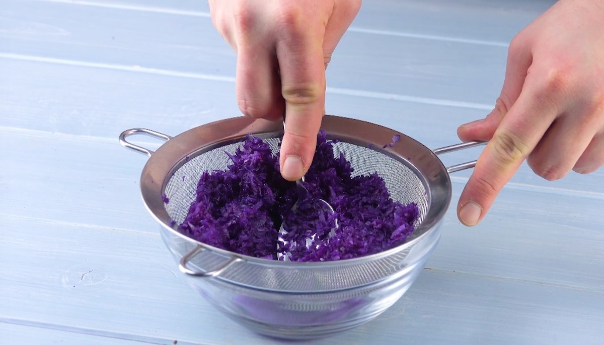 Rotkohl wird mit einem Löffel durch ein Sieb gepresst