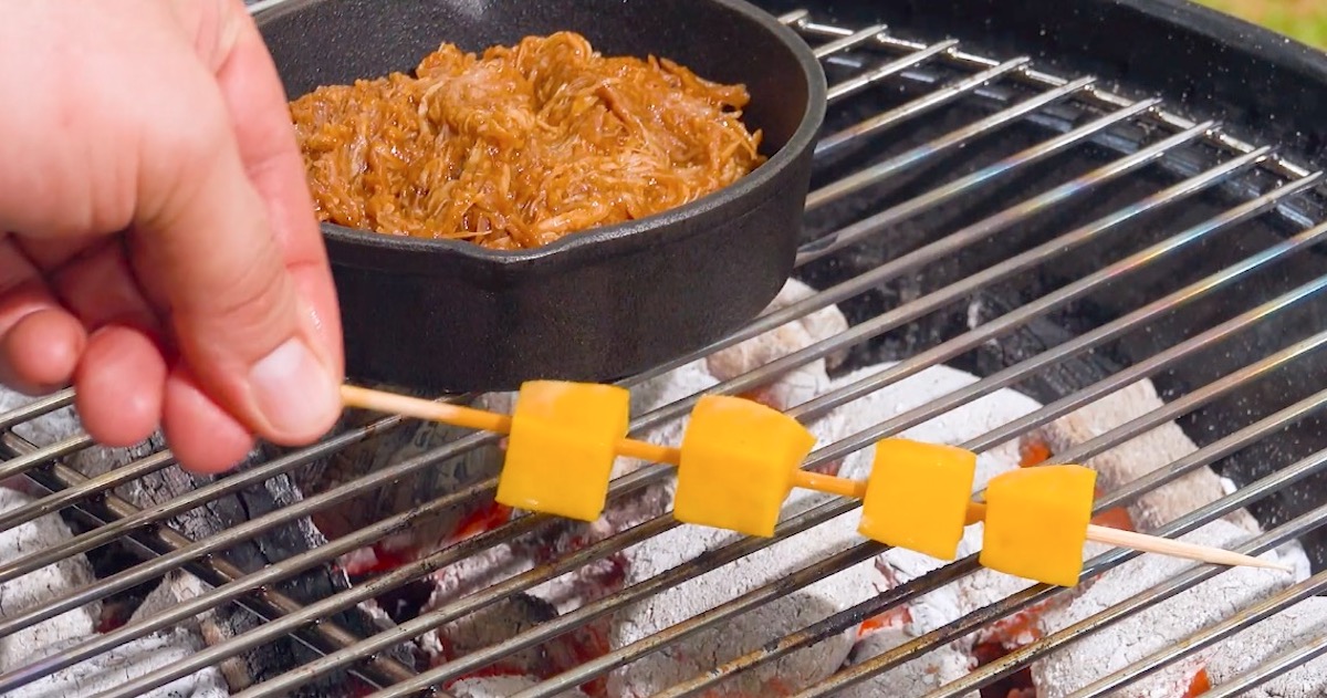 Pulled Chicken in Schale und Ananasstücken am Spieß auf Grill