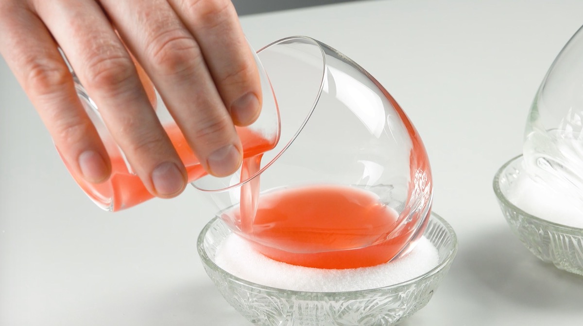 Rote Gummibärenflüssigkeit wird in schräg stehendes Glas gefüllt