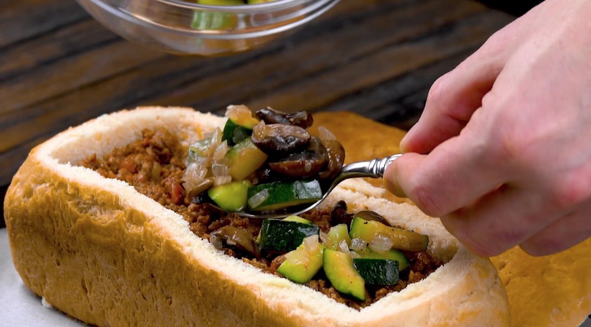 Brotlaib wird mit Hackfleisch und Gemüse gefüllt