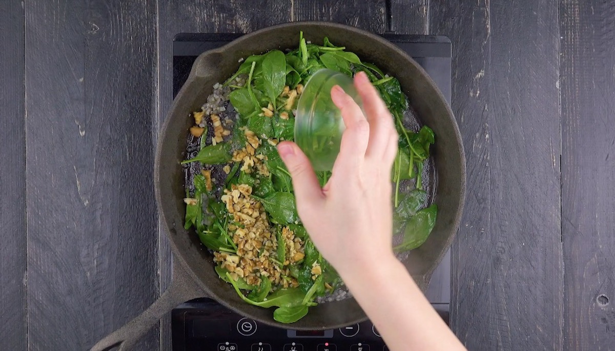 Walnüsse und Spinat werden in Pfanne gedünstet