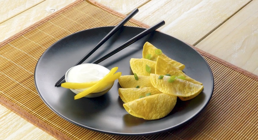 Ei-Ravioli mit Reisfüllung und Crème fraîche in Schale auf Teller