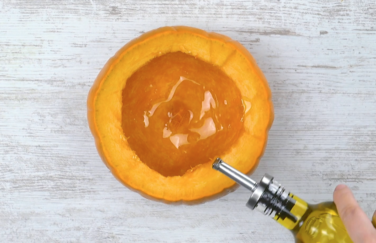 Ausgehöhlter Kürbis wird mit von innen mit Olivenöl beträufelt