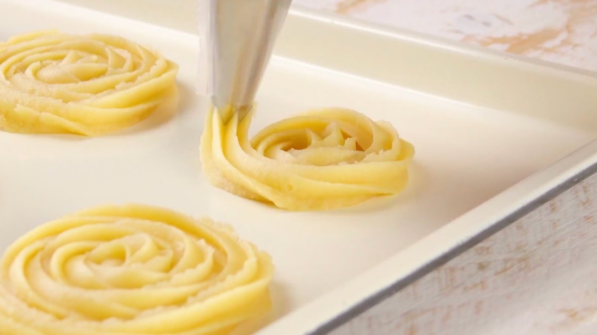 Brandteig wird auf Backblech kreisförmig aufgespritzt