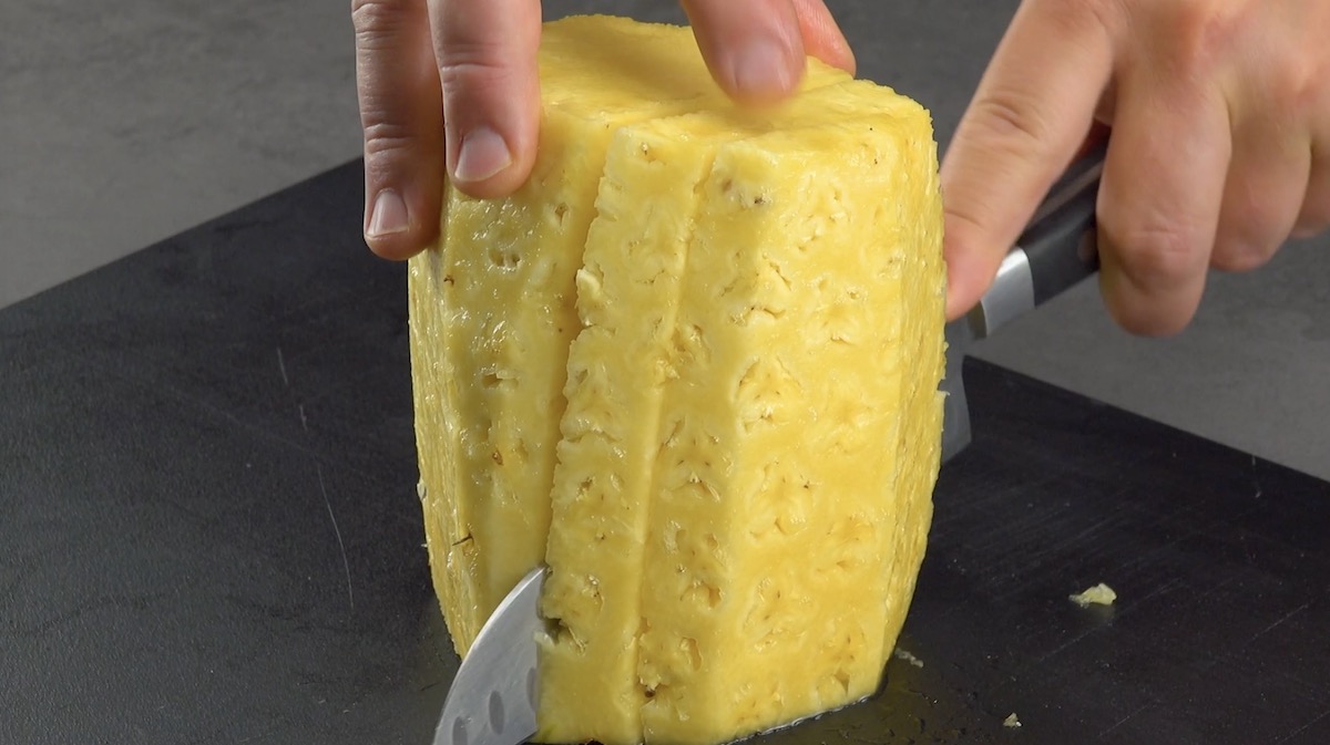 Geschälte Ananas wird in große Scheiben geschnitten