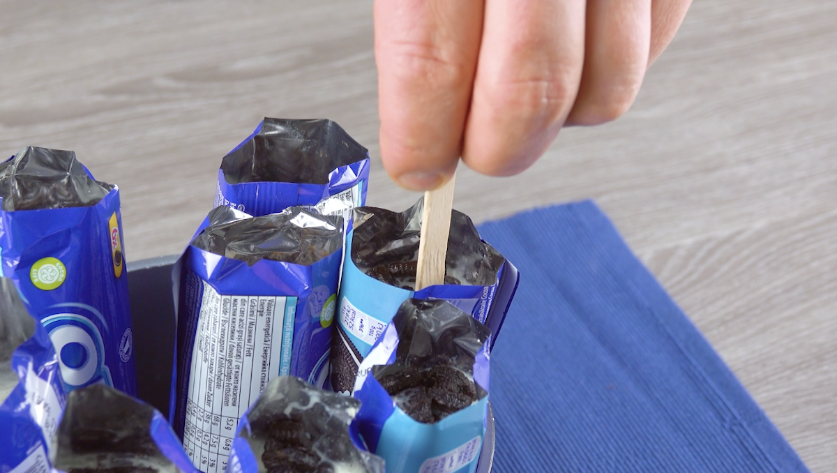Stiel wird in flüssige Eismasse in Oreo-Verpackungen gesteckt