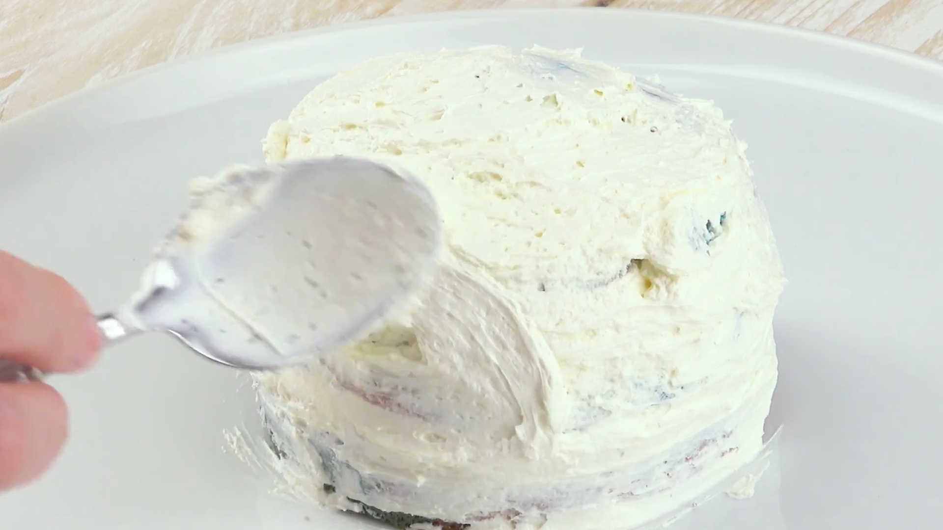 Kleiner Kuchen wird mit weißer Buttercreme eingestrichen