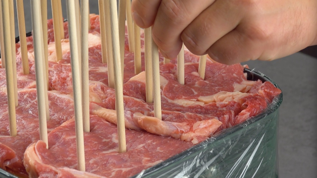 Holzspieße werden von oben in Zutaten in Backform gesteckt