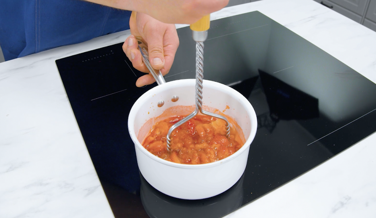 Erdbeeren werden eingekocht und mit Kartoffelstampfer zerdrückt