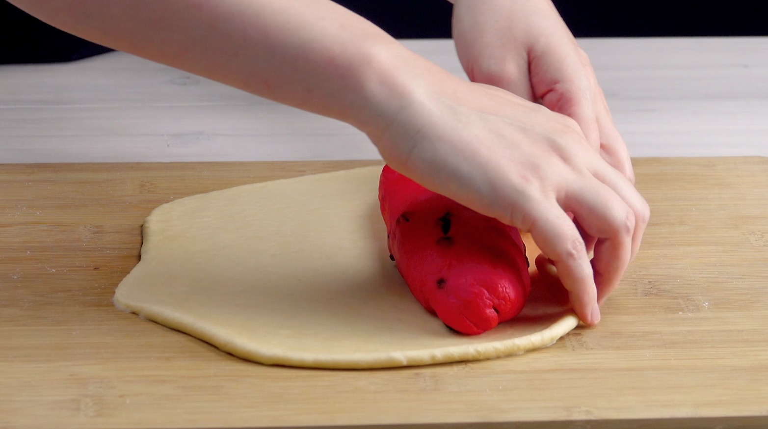 Roter Brotteig mit Rosinen wird in weißen Brotteig eingewickelt