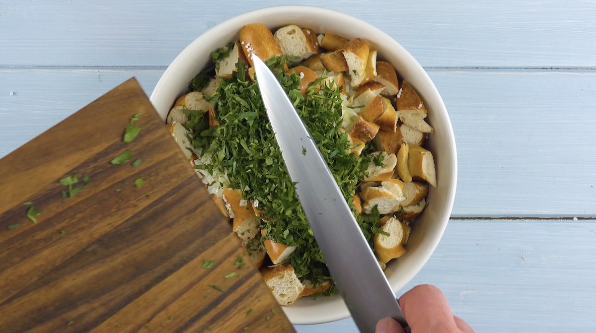 Fein gehackte Petersilie wird mit Messer von Brett in Schüssel gegeben