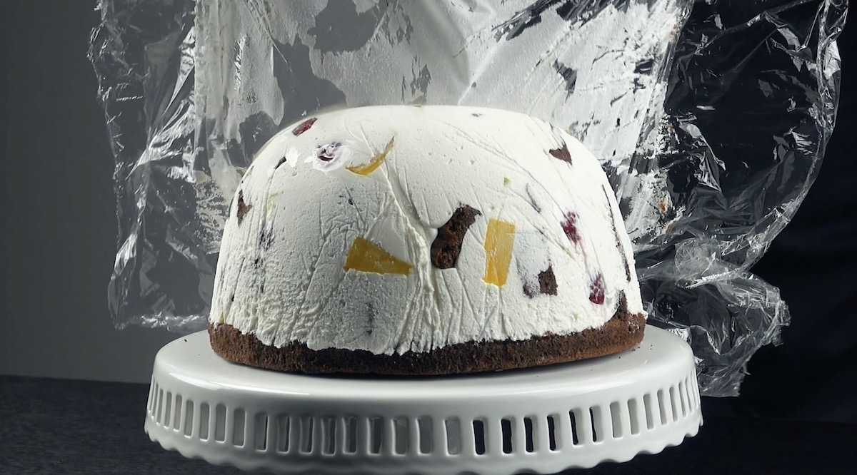 Nach dem Kühlen wird die Kuppeltorte auf Tortenplatte gestellt und die Frischhaltefolie entfernt