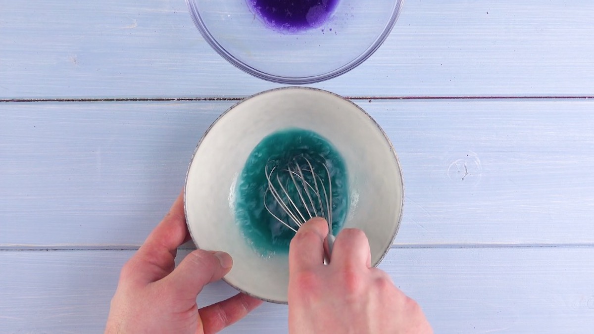 Zitronensaft wird zu Eiweiß mit Rotkohlsaft gegeben und mit Schneebesen umgerührt