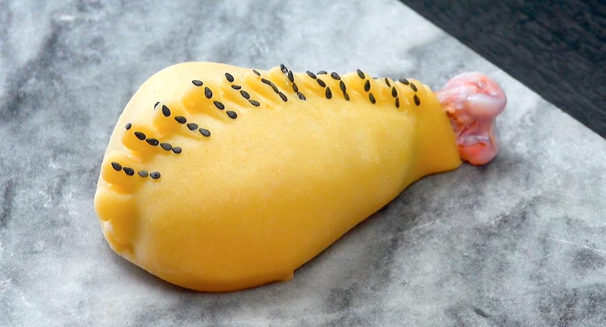 Teigkamm wird zusammengedrückt und so mit schwarzem Sesam garniert, das die Keule aussieht wie zugenäht