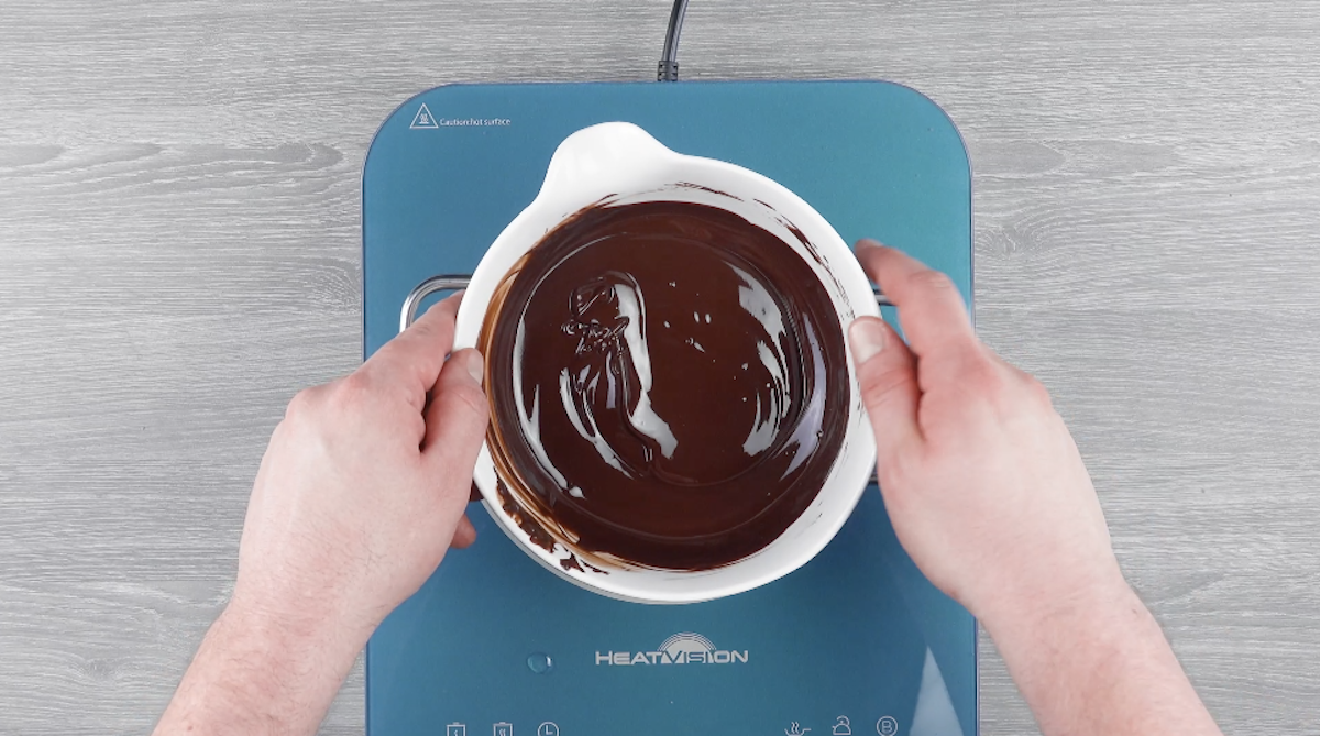 Schokoglasur wird in einer Schüssel über einem Wasserbad geschmolzen