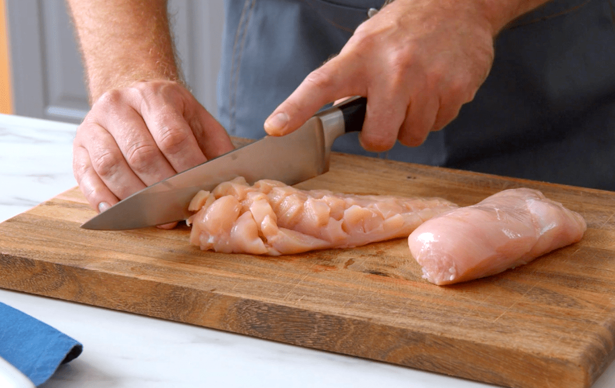 Rohe Hähnchenbrüste werden mit einem Messer eingeschnitten