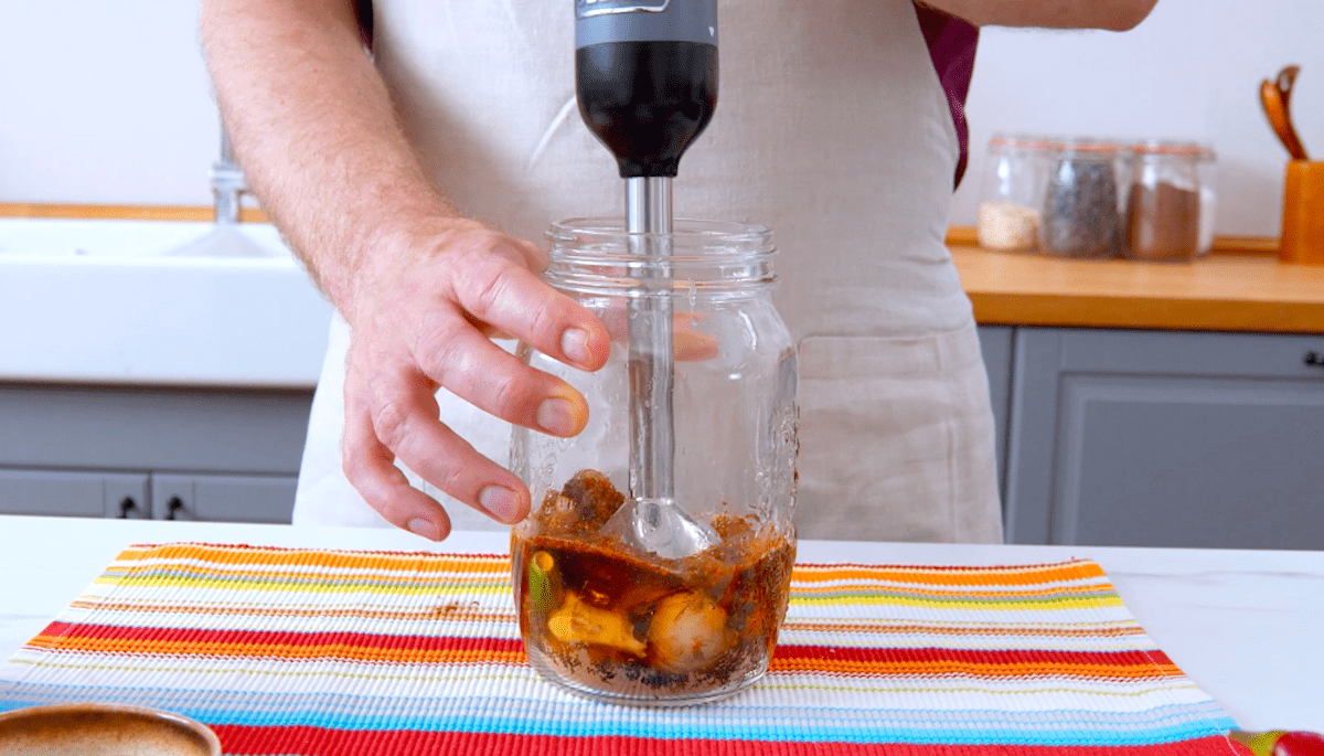 Eine Marinade wird in einem hohen Glasgefäß mit einem Pürierstab zubereitet