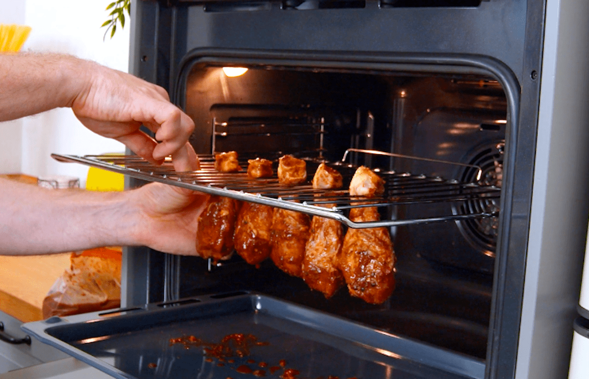 Marinierte Hähnchenschenkel werden in ein Ofenrost in ein Ofen gehangen