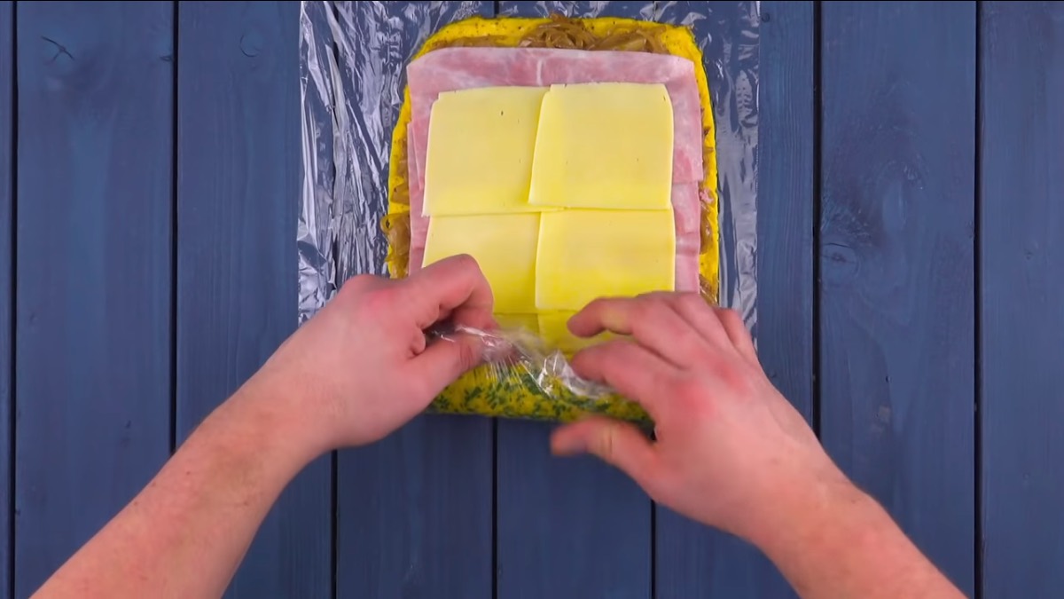 Omelett-Rolle mit Schinken-Käse-Füllung wird aufgerollt