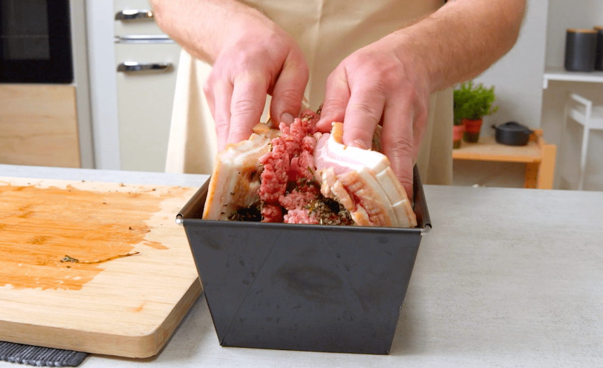 Gefüllter Schweinebauch wird in eine Kastenform gelegt