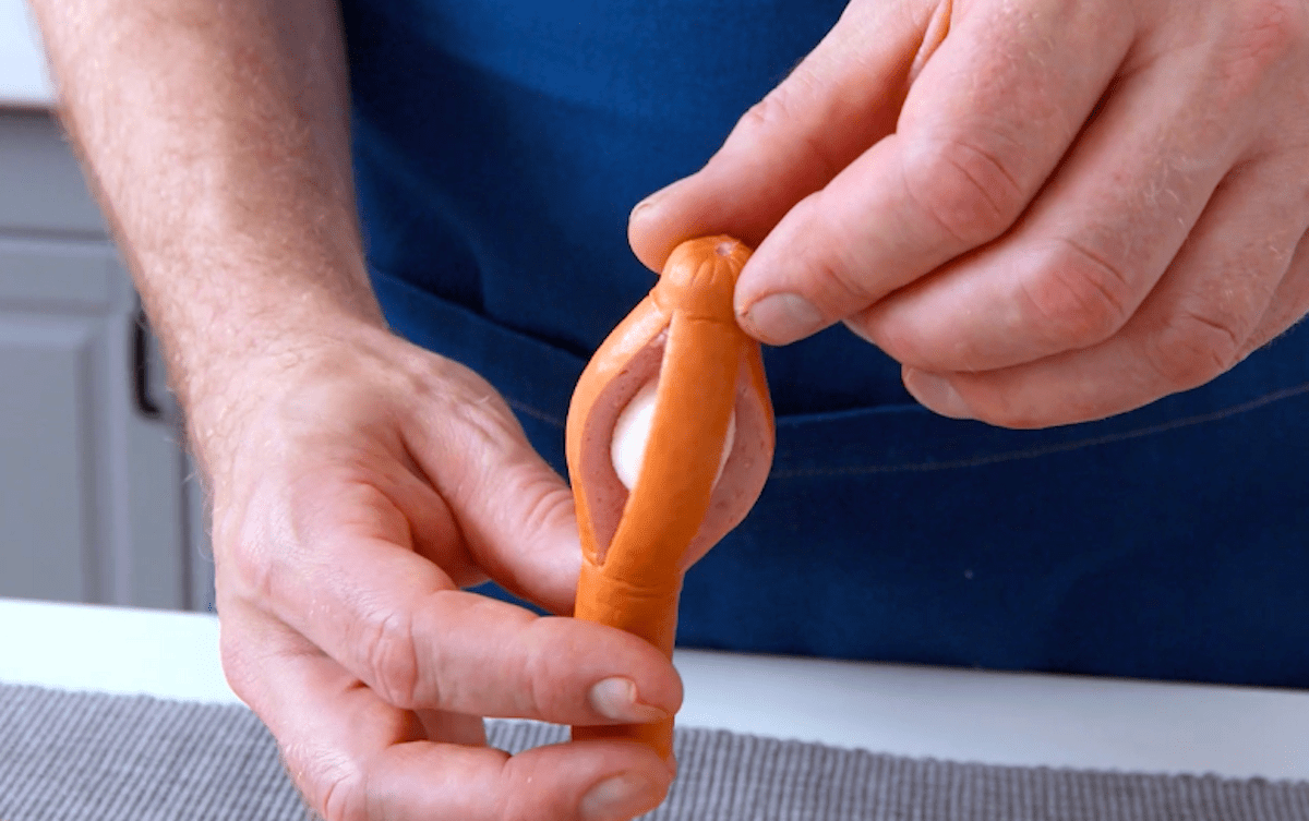 Ein Würstchen wurde eingeschnitten, sodass man eine kleine Mozzarella-Kugel in die Mitte stecken kann