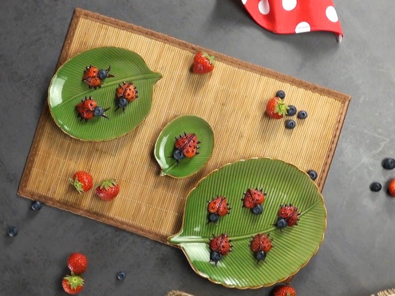 Tricks mit Erdbeeren: süße Marienkäfer aus Erdbeeren auf Tellern in der Draufsicht.