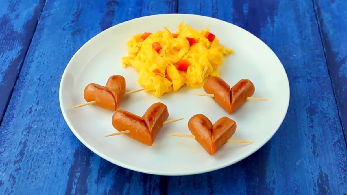 4 kleine Würstchen-Herzen mit Rührei auf Teller