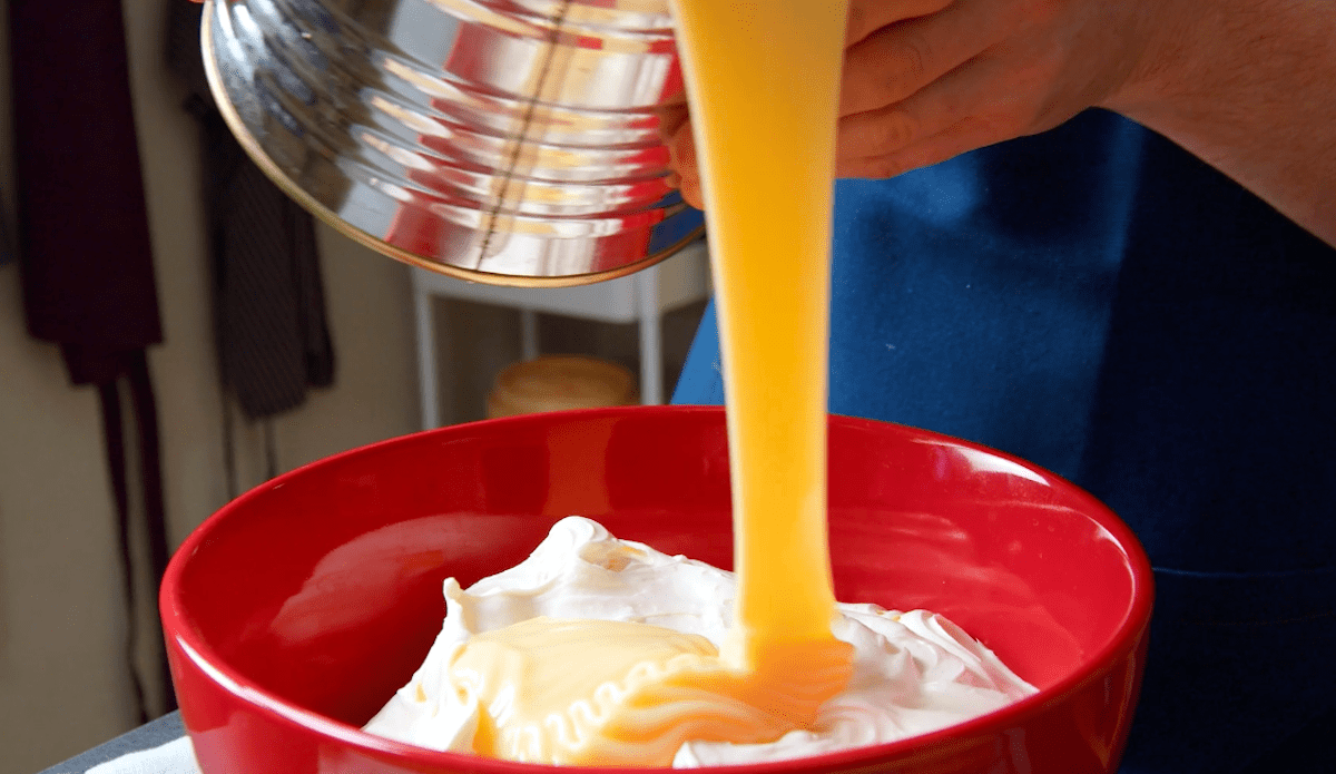 Kondensmilch wird zu steif geschlagener Sahne in eine Schüssel gegeben